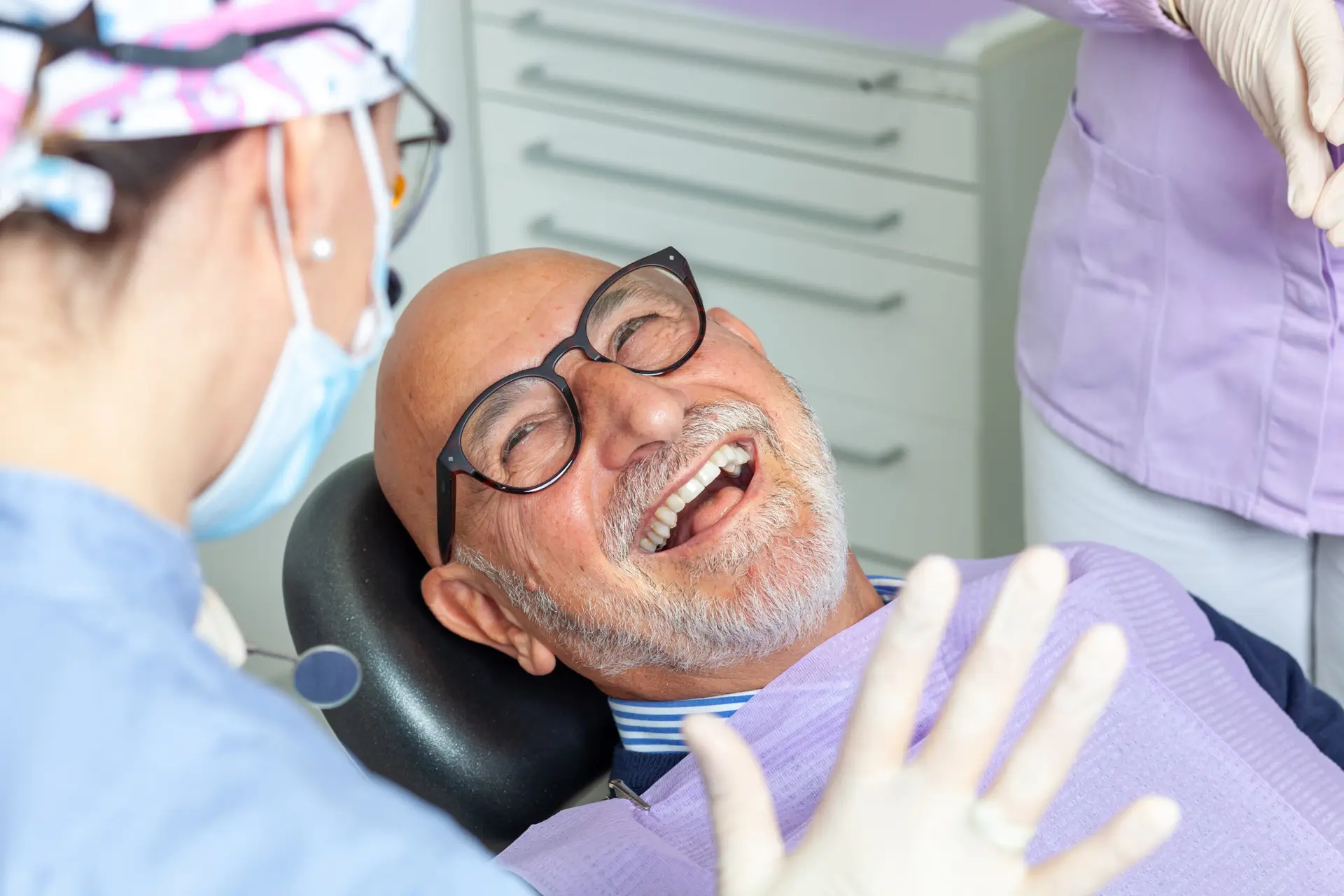 senior man laughing during dental checkup with female dentist